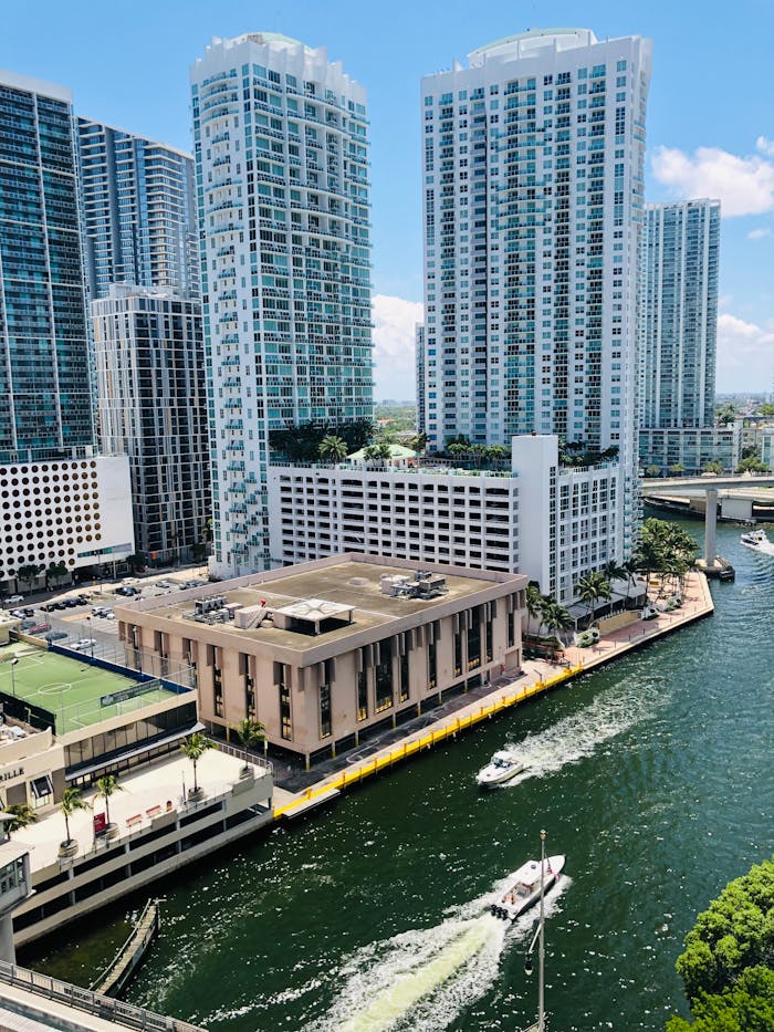 gallery-6 Aerial view of modern skyscrapers by a lively waterfront in a vibrant city.